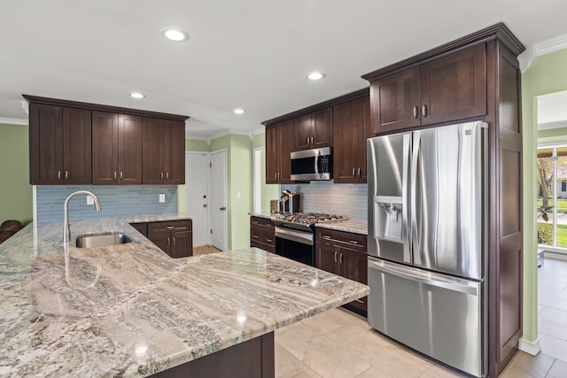 kitchen featuring ornamental molding, light stone counters, a sink, appliances with stainless steel finishes, and backsplash