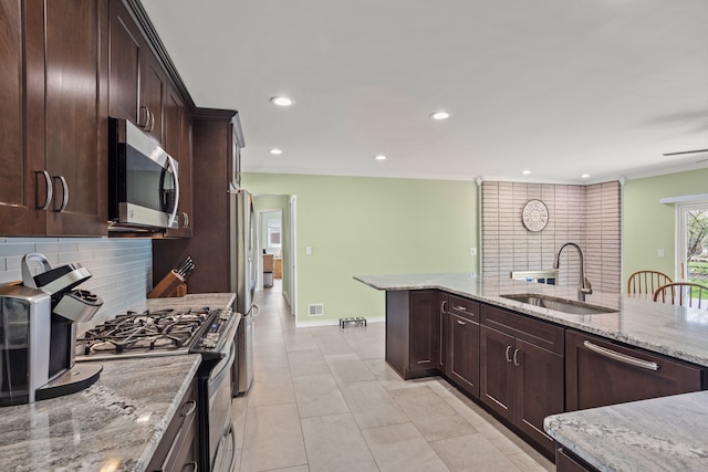 kitchen featuring appliances with stainless steel finishes, light stone counters, a sink, recessed lighting, and backsplash