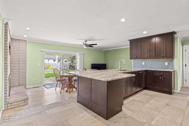 kitchen featuring crown molding, a peninsula, a sink, and dark brown cabinets