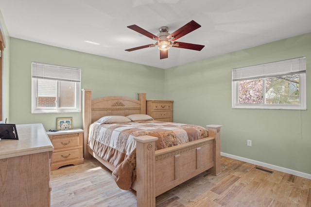 bedroom featuring baseboards, a ceiling fan, light wood finished floors, and visible vents