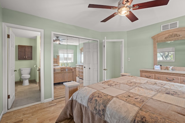 bedroom with connected bathroom, visible vents, multiple windows, and light wood finished floors