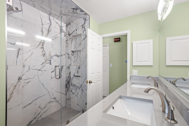 bathroom with a sink, a marble finish shower, and double vanity