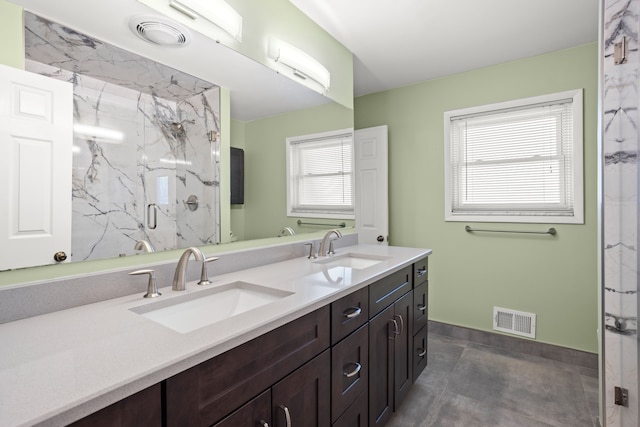 bathroom with visible vents, a sink, a marble finish shower, and double vanity