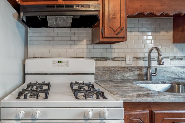 34038 Caseville Ct, Westland, MI 48186 - kitchen featuring white gas range, a sink, decorative backsplash, brown cabinets, and under cabinet range hood