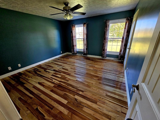 empty room featuring baseboards, a textured ceiling, ceiling fan, and wood-type flooring