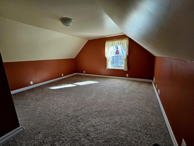 additional living space with vaulted ceiling, baseboards, and carpet floors