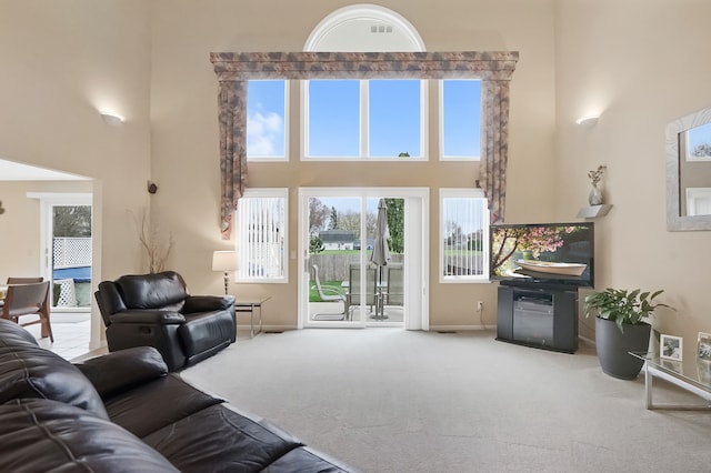 living room with baseboards, a high ceiling, and carpet flooring