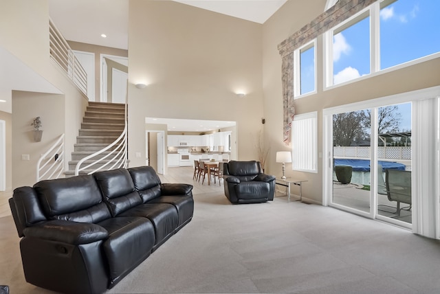 living area featuring stairway, baseboards, a high ceiling, and carpet
