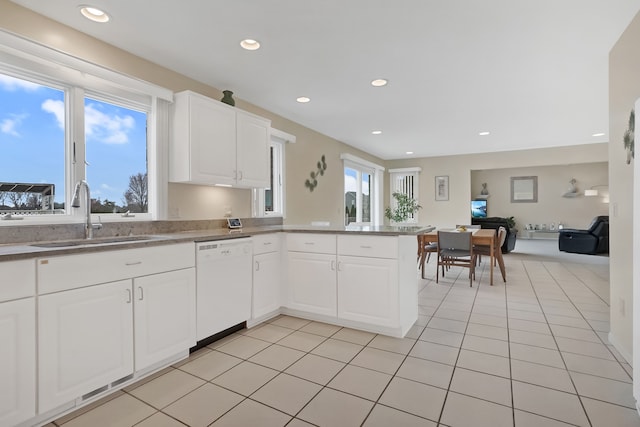 kitchen with a sink, open floor plan, light tile patterned floors, dishwasher, and a peninsula