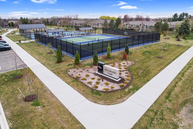 view of property's community featuring fence, a yard, a residential view, and a tennis court