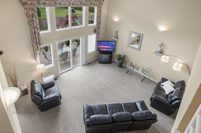 living area with a high ceiling, carpet flooring, and baseboards