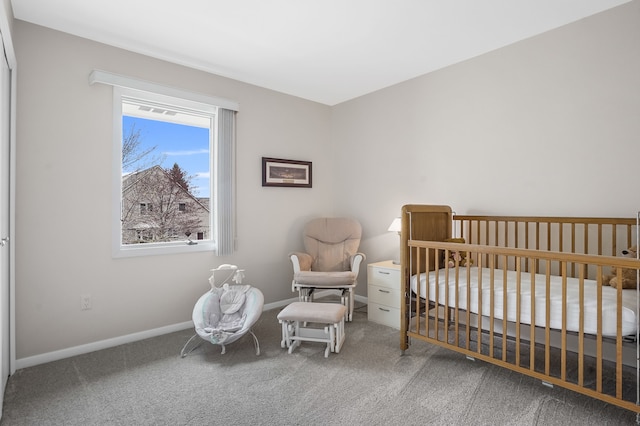 carpeted bedroom featuring a nursery area and baseboards