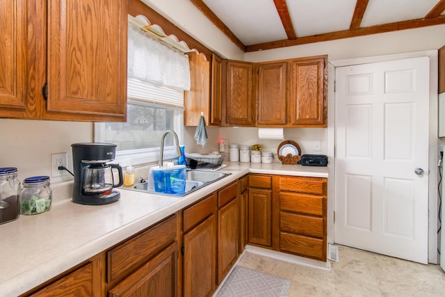 kitchen featuring brown cabinets, light countertops, and a sink