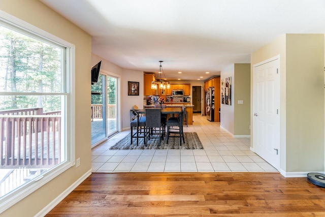 dining area with baseboards, a chandelier, and light wood-type flooring