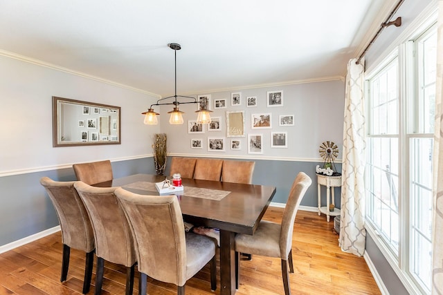 dining area featuring light wood finished floors, baseboards, and ornamental molding