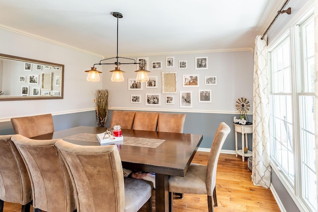 dining area with baseboards, ornamental molding, and light wood finished floors