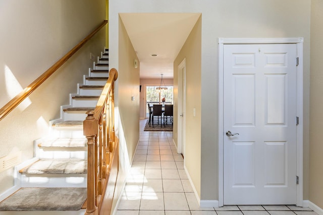 stairway with tile patterned flooring, baseboards, and an inviting chandelier