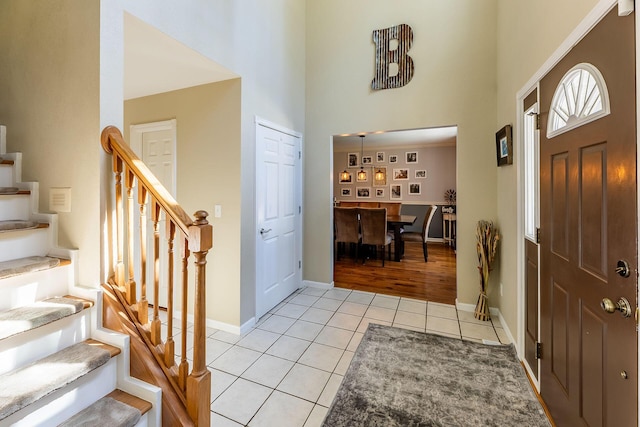 entryway featuring stairway, baseboards, a high ceiling, and light tile patterned floors
