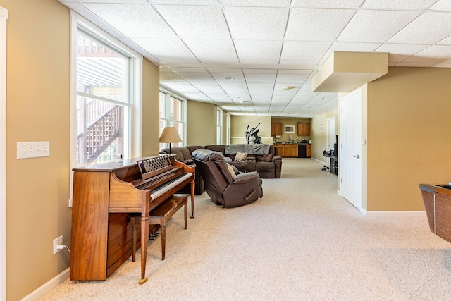 carpeted living room with a drop ceiling and baseboards