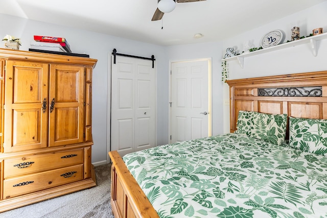 bedroom with a ceiling fan, a closet, light colored carpet, and a barn door