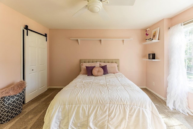 carpeted bedroom featuring a barn door, a ceiling fan, and baseboards