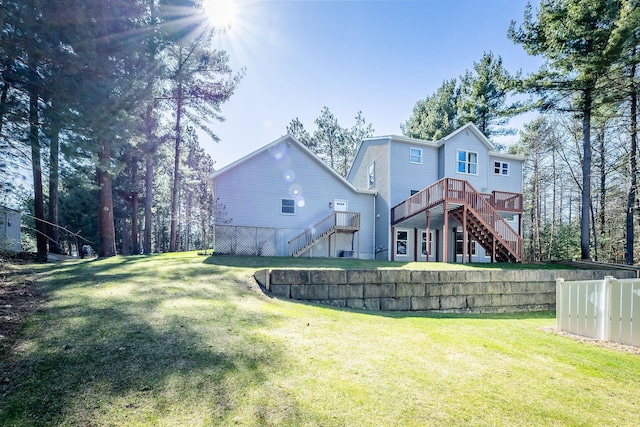 rear view of house featuring fence, a wooden deck, a yard, and stairs