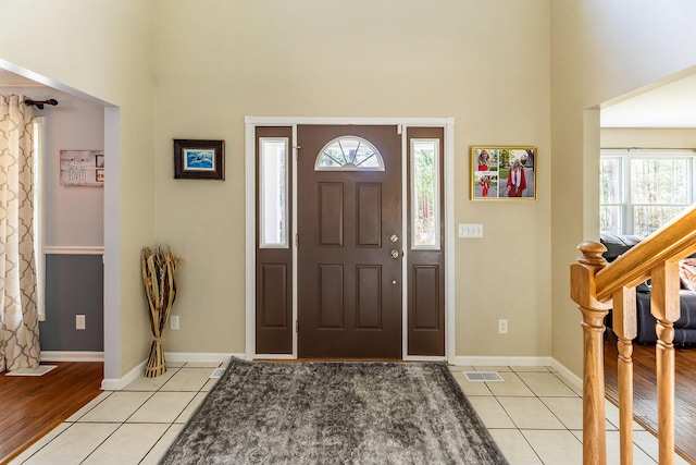 foyer featuring visible vents, a towering ceiling, and light tile patterned floors