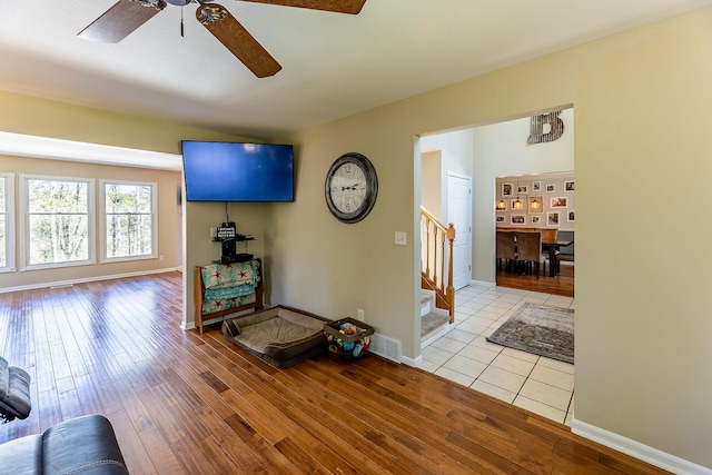living room with baseboards, a ceiling fan, wood finished floors, and stairway