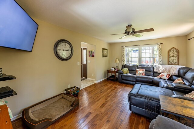 living area featuring wood-type flooring, baseboards, and ceiling fan