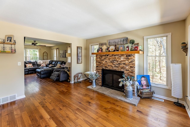 living area featuring baseboards, hardwood / wood-style floors, visible vents, and a fireplace