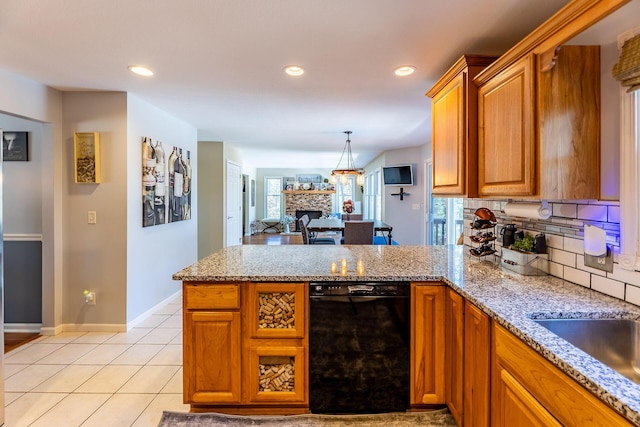 kitchen with light stone counters, brown cabinetry, dishwasher, baseboards, and a peninsula
