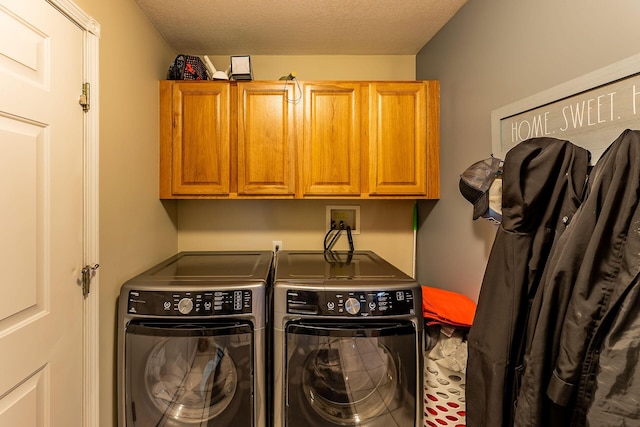 washroom featuring cabinet space, a textured ceiling, and washer and dryer