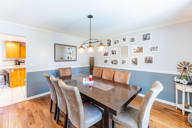 dining space with light wood-type flooring, baseboards, and ornamental molding