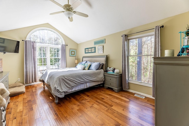 bedroom with light wood-style floors, vaulted ceiling, visible vents, and a ceiling fan