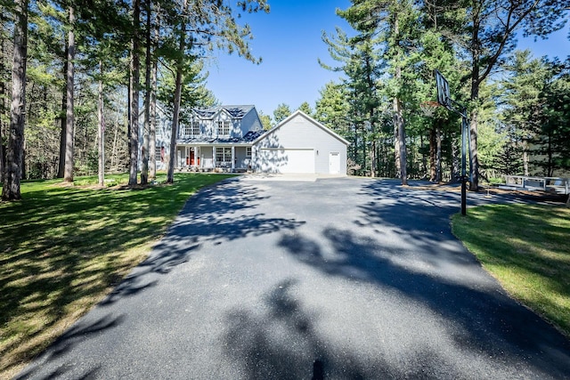 view of front of home with an attached garage, driveway, a front yard, and covered porch