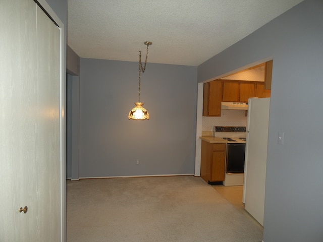 kitchen with under cabinet range hood, light countertops, white appliances, brown cabinetry, and light colored carpet