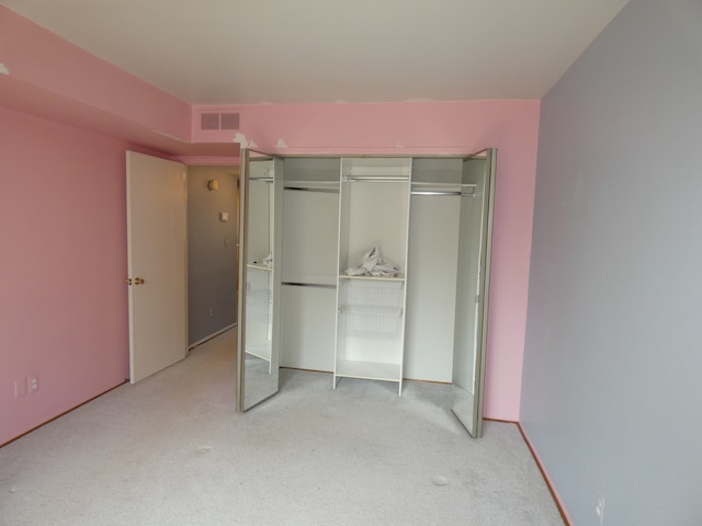 unfurnished bedroom with a closet, visible vents, and carpet
