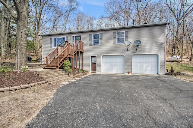 view of front of house with an attached garage, driveway, and stairs