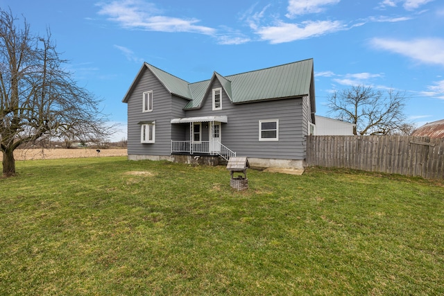 back of property with fence, a yard, and metal roof