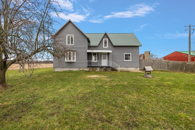 rear view of property with fence, a yard, and metal roof