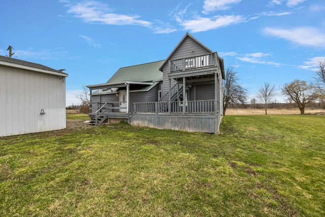 rear view of property with a yard, stairs, metal roof, and a deck