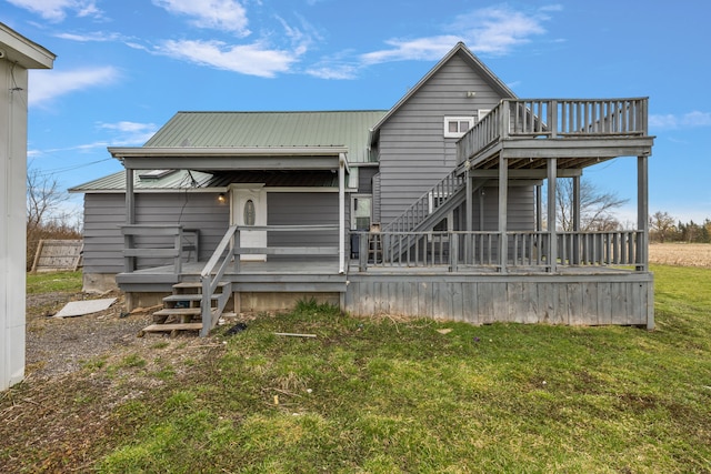 back of house featuring a lawn, a wooden deck, and metal roof