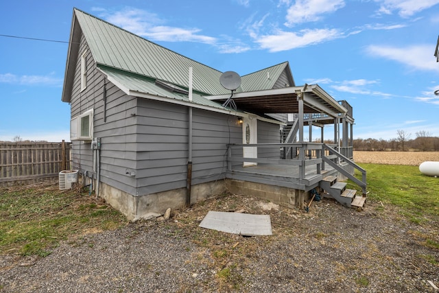 view of home's exterior with fence, a deck, and metal roof