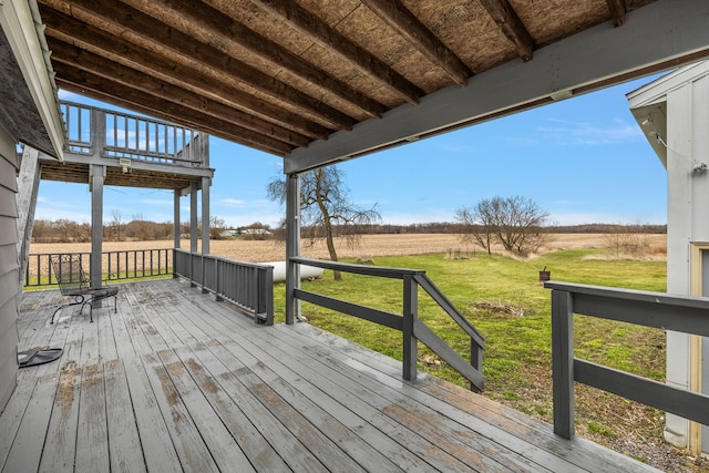 wooden terrace with a rural view and a yard