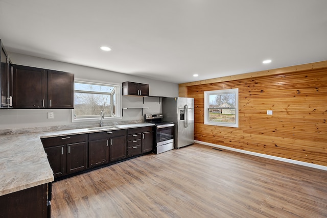 kitchen with light wood-style floors, dark brown cabinets, stainless steel appliances, and a sink