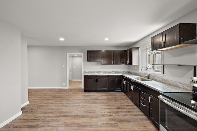 kitchen featuring recessed lighting, stainless steel range with electric cooktop, dark brown cabinets, a sink, and light wood-style flooring