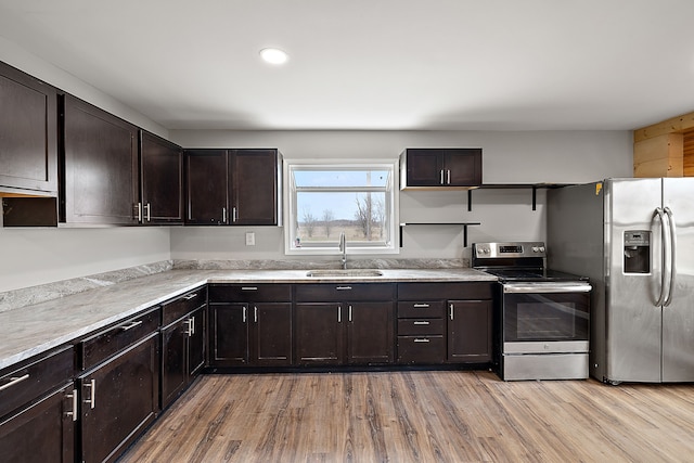 kitchen featuring light wood-style flooring, appliances with stainless steel finishes, dark brown cabinetry, and a sink