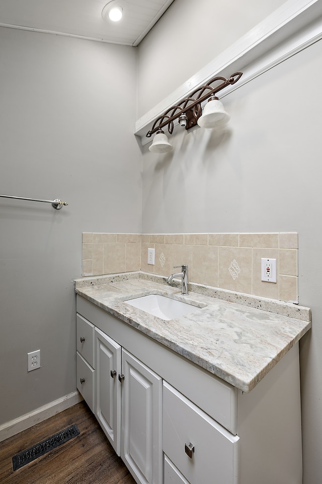 bathroom with wood finished floors, visible vents, vanity, and tasteful backsplash