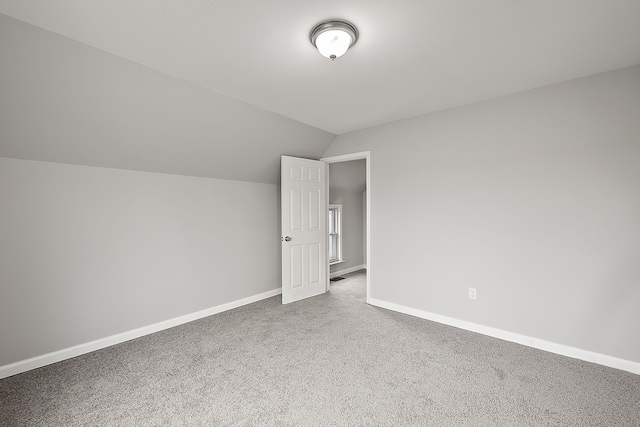 unfurnished bedroom with baseboards, lofted ceiling, and carpet