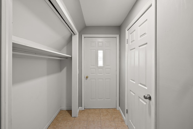 doorway to outside featuring light tile patterned flooring, vaulted ceiling, and baseboards
